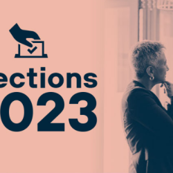 Deux personnes sont sur une affiche. L'affiche mentionne « Élections 2023 » avec une dessin d'une boite et d'une main.