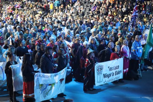 A bunch of people gathering after the grand march of the National Gathering of Elders. Dozens of nations throughout Canada are represented. Photo was taken under a blue light.