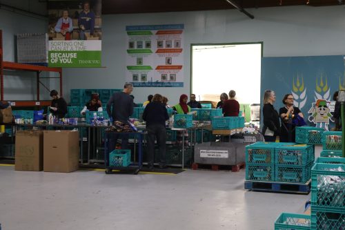 Volunteers at Edmonton's Food Bank hard at work making sure the needs of the community are met. They are all at tables. The photo was taken inside.