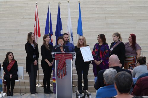 Edmonton city councilors present members of the Métis Nation of Alberta with a proclamation on behalf of Mayor Amarjeet Sohi. The Canadian, Albertan, Metis, Metis Nation of Alberta, and Edmontonian flags stand behind them.