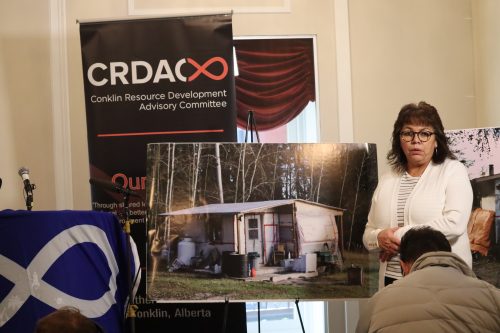 Grace Richards, Membership Director of Conklin Community Association & CRDAC Board Director, points at a picture of a trailer with a make-shift structure built to attach to it. This is what Grace lives in because of the lack of suitable housing in Conklin. Photo was taken inside.