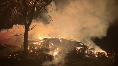 At nighttime a pile of burning debris glows orange after a barn used for feed and equipment storage burned to the ground.
