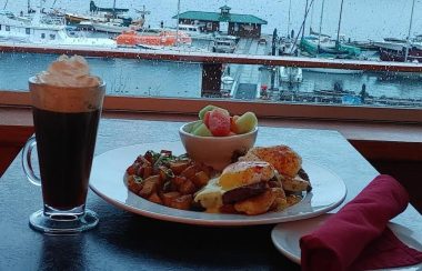 A burger, beer and fries on a counter overlooking a marina filled with boats