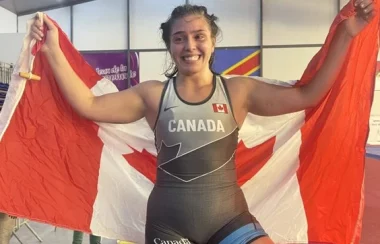 une femme avec un maillot d'athlètes tenant le drapeau du Canada avec ses deux mains