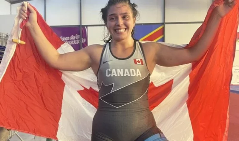 une femme avec un maillot d'athlètes tenant le drapeau du Canada avec ses deux mains