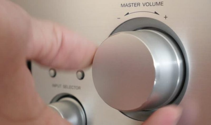 A hand turning the volume dial lower.