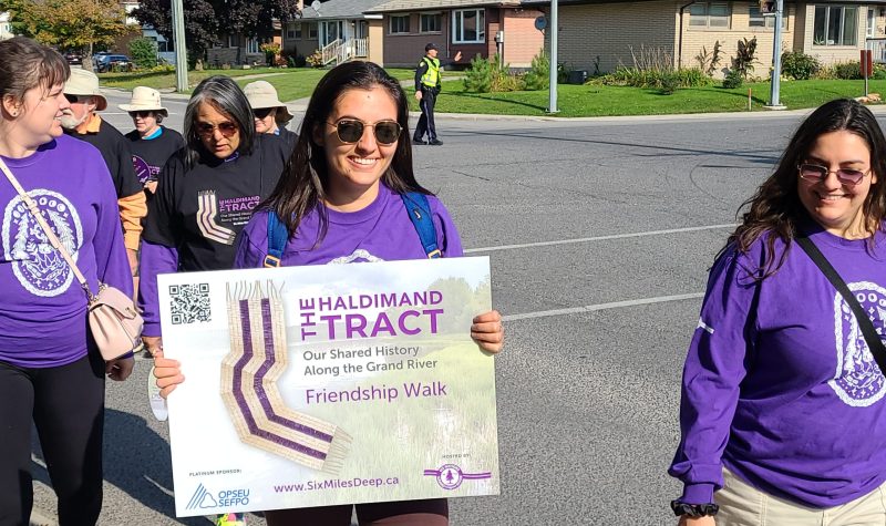 Purple T-shirt wearing individuals walk holding signs for The Friendship Walk