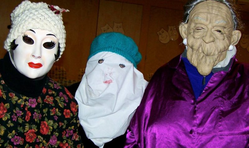 Trois personnes costumées avec masques, chapeaux et habits.