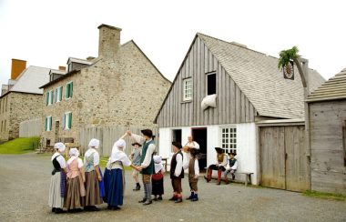 Des enfants en costumes authentiques dansant dans la rue avec des anciens bâtiments en arrière plan.