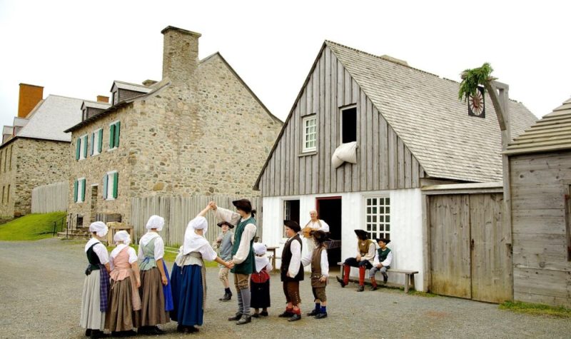 Des enfants en costumes authentiques dansant dans la rue avec des anciens bâtiments en arrière plan.