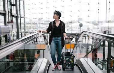 Une femme en haut d'un Escalator, elle a une valise, elle a l'air d'arriver pour découvrir et s'installer.