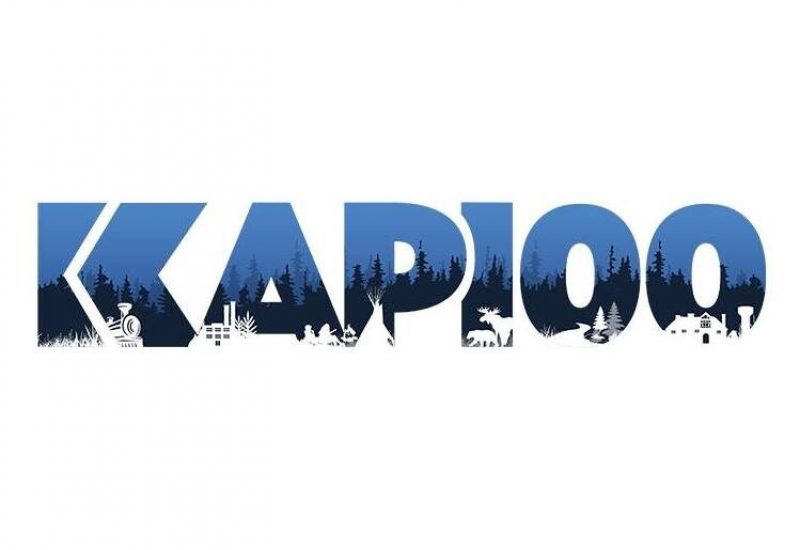 Le nouveau logo des festivités du 100e de Kapuskasing. On peut y voir le terme Kap100 en bleu et noir avec des petits arbres dessinés en blanc dans le bas du logo.