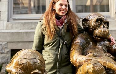 Laurence Vallières souriante avec ses chimpanzés en bronze.