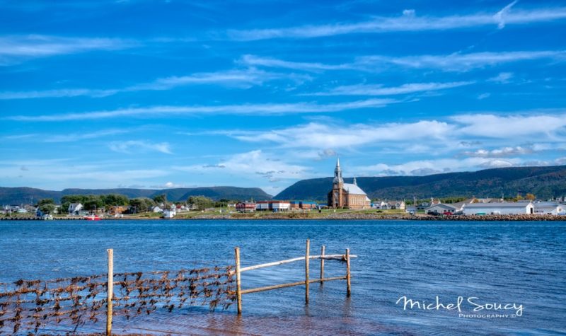 Un village au pied des montagnes avec la mer en avant plan.