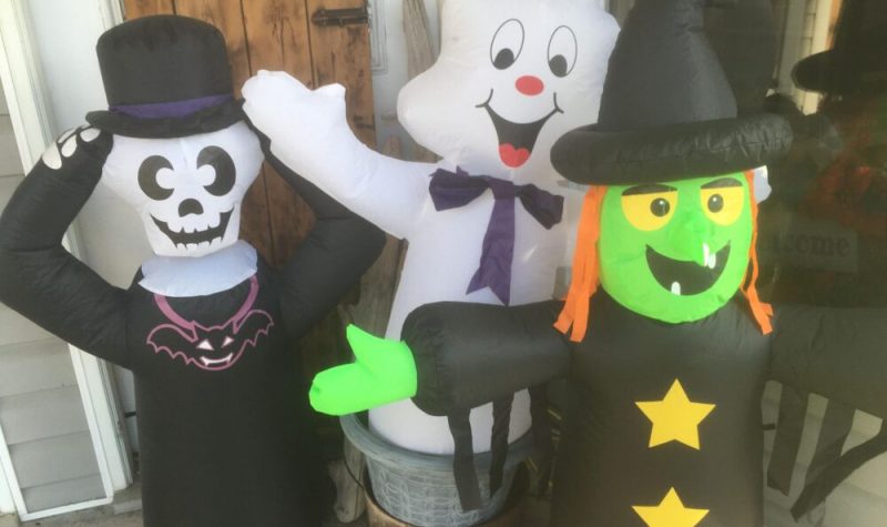 Un squelette, un fantôme et une sorcière gonflable en face d'un magasin comme décorations pour l'Halloween