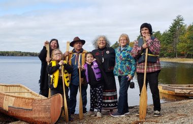 Des gens debout à côté d'un canot sur un lac.