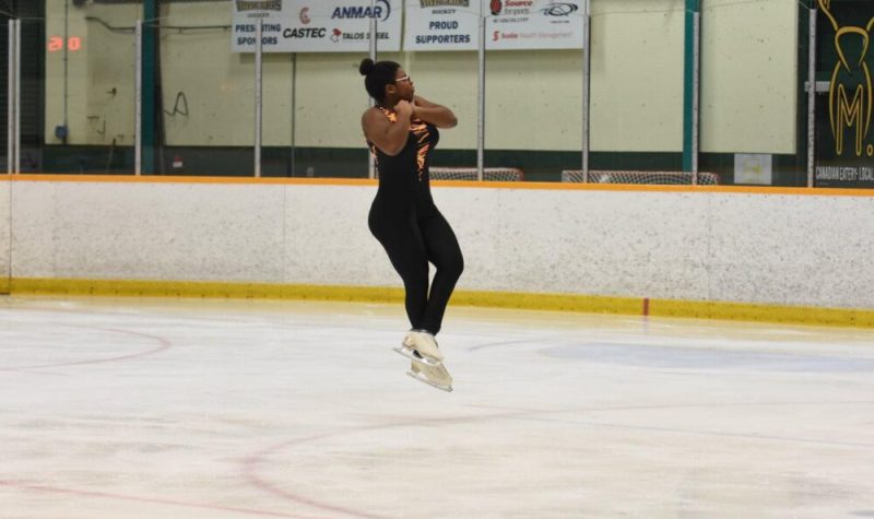 Une jeune patineuse qui fait une figure dans les airs sur la patinoire