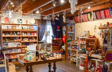 L'intérieur de la boutique, une bibliothèque au fond avec une table dans le centre et des étagères sur les côtés.