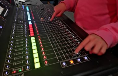 Jeune avec chandail rouge manipulant une console de son.