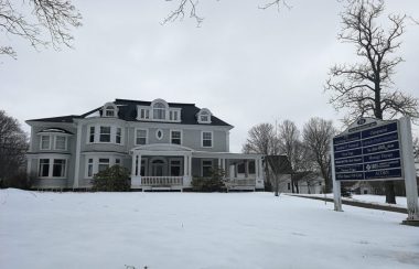 Historic white and grey mansion on a winter day.