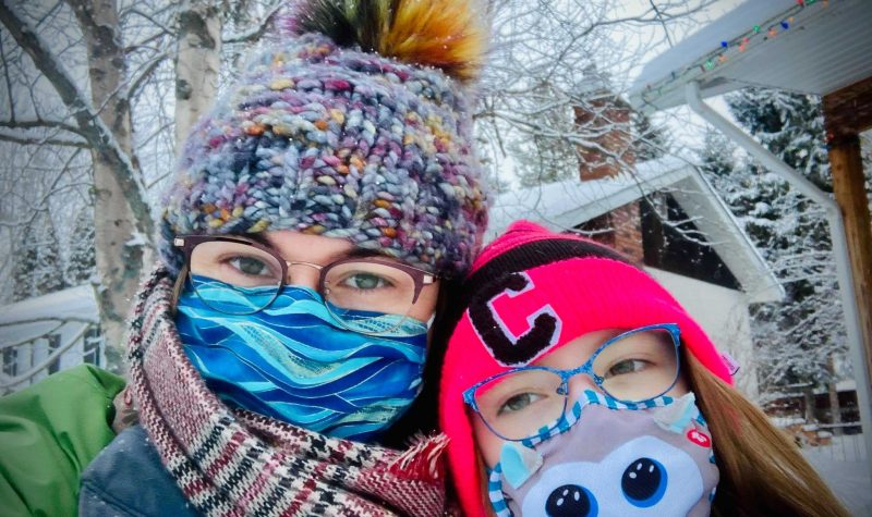 A woman and her child in masks, hats and scarves.