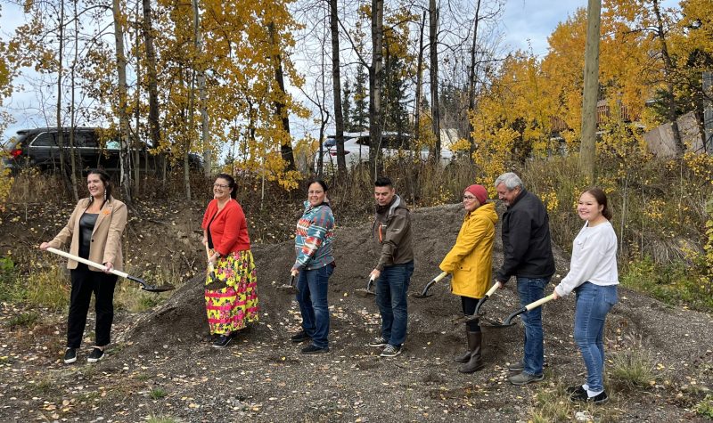Seven people standing outside on a fall day, with shovels' holding dirt