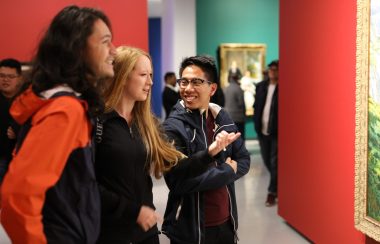 Deux femmes et un homme admirent les œuvres d'art exposées lors de l'événement de l'année dernière.