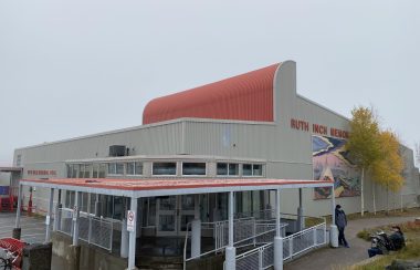 Un vaste édifice gris et orangé, sous un ciel gris.