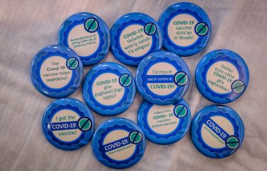 11 macarons bleus, sur lesquels ont lit « j'ai reçu le vaccin contre la COVID-19 ! », dans les 11 langues officielles des T.N.-O.