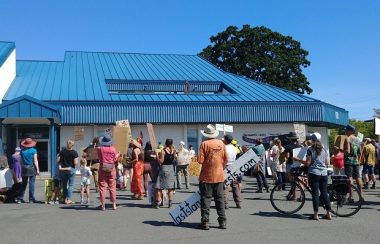 A group of about 30 people stands outside of Comox Valley RCMP detachment