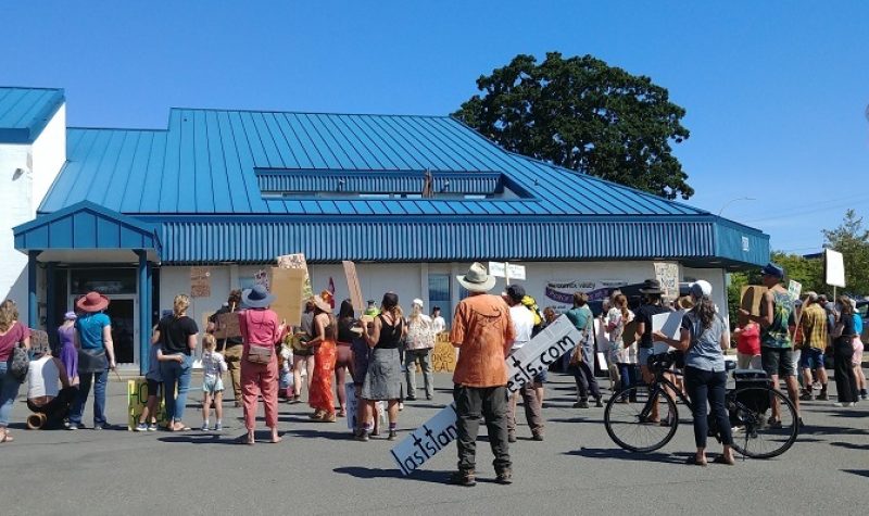 A group of about 30 people stands outside of Comox Valley RCMP detachment