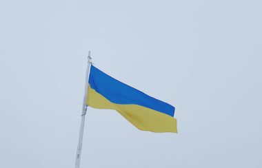 Le drapeau Ukrainien flotte au vent. sous un ciel gris.