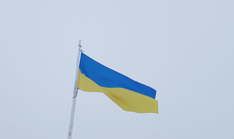 Le drapeau Ukrainien flotte au vent. sous un ciel gris.