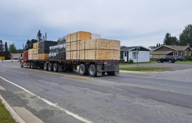 Camion poids lourd avec des planches de bois chargées circulant dans un rue