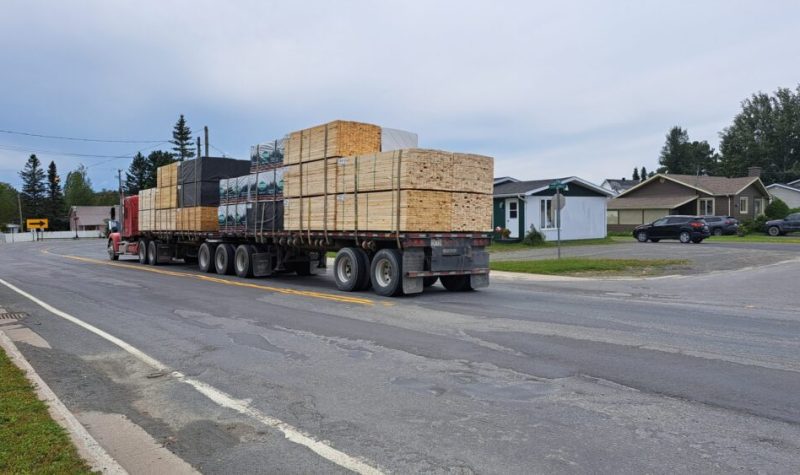 Camion poids lourd avec des planches de bois chargées circulant dans un rue