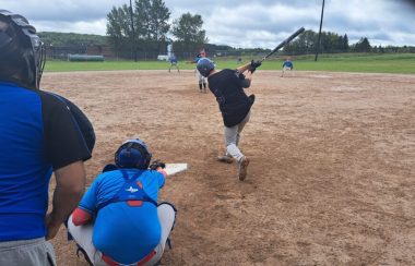 Lors d'un match de softball, un batteur pourtant un chandail noir s'élance