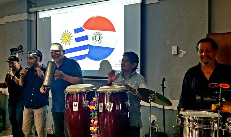 El grupo de Música la Banda Loca tocan delante de las banderas de Uruguay y Paraguay