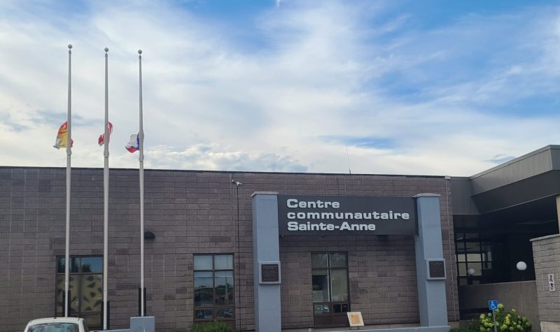 Facade du centre communautaire Sainte-Anne de Fredericton, les drapeaux sont en bernes.