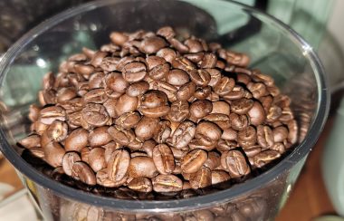Roasted coffee beans displayed in a glass bowl.