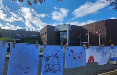 dessins d'enfants accrochés sur une corde à linge devant le centre communautaire Samuel-de-Champlain