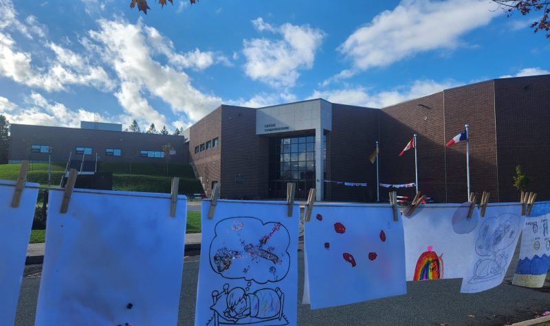 dessins d'enfants accrochés sur une corde à linge devant le centre communautaire Samuel-de-Champlain