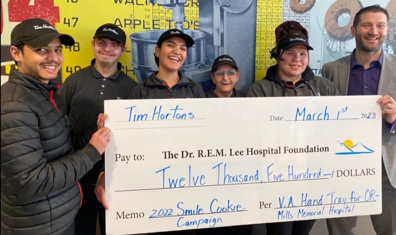 Six people holding a large check smiling