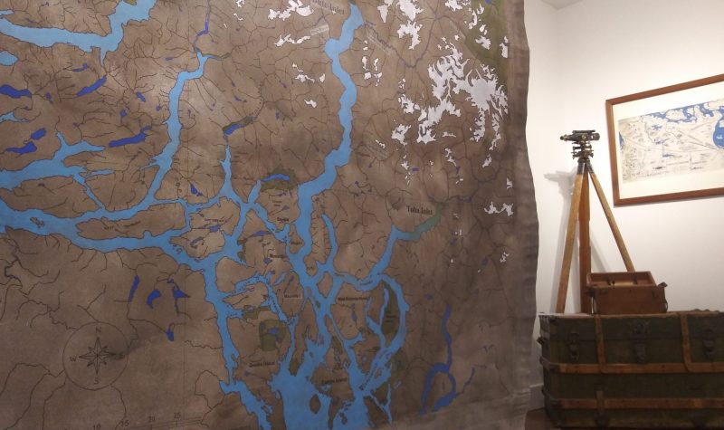 Large scale map hangs like a tapestry from the ceiling of a museum exhibit.