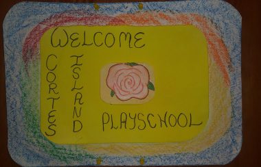 A handmade sign reads ‘Cortes Island Playschool’, colored with crayons.