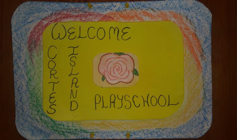 A handmade sign reads ‘Cortes Island Playschool’, colored with crayons.