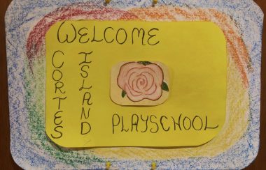 Hand drawn sign reads, “Welcome to Cortes Island Playschool”.