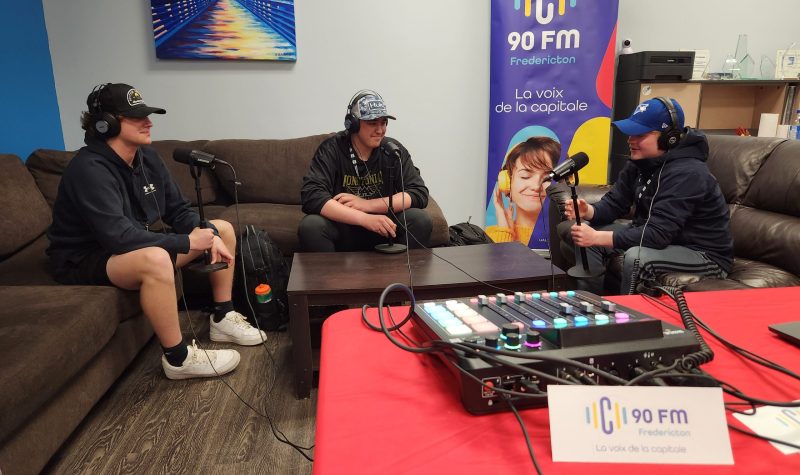 3 élèves installé sur un canapé, ils ont des casques et des micros et sont en train d'enregistrer une discussion en Podcast.