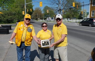 Lions Club Members Stand with their Service Excellence Plaque on the street in Bath