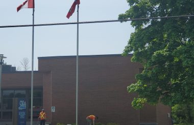 Municipal building in background with two township workers working on grounds