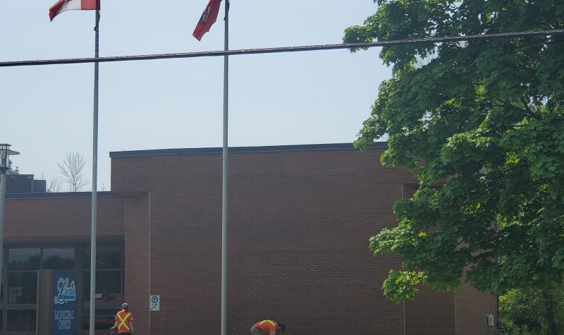 Municipal building in background with two township workers working on grounds